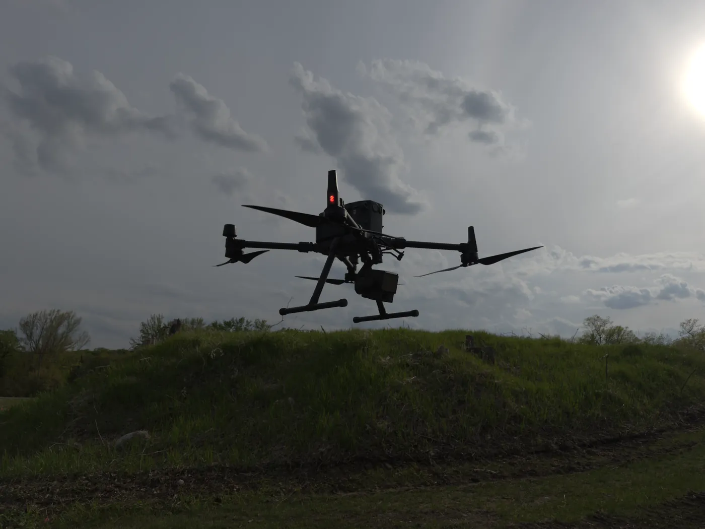 Northern Drone LiDAR drone silhouetted against the sky over a grassy slope