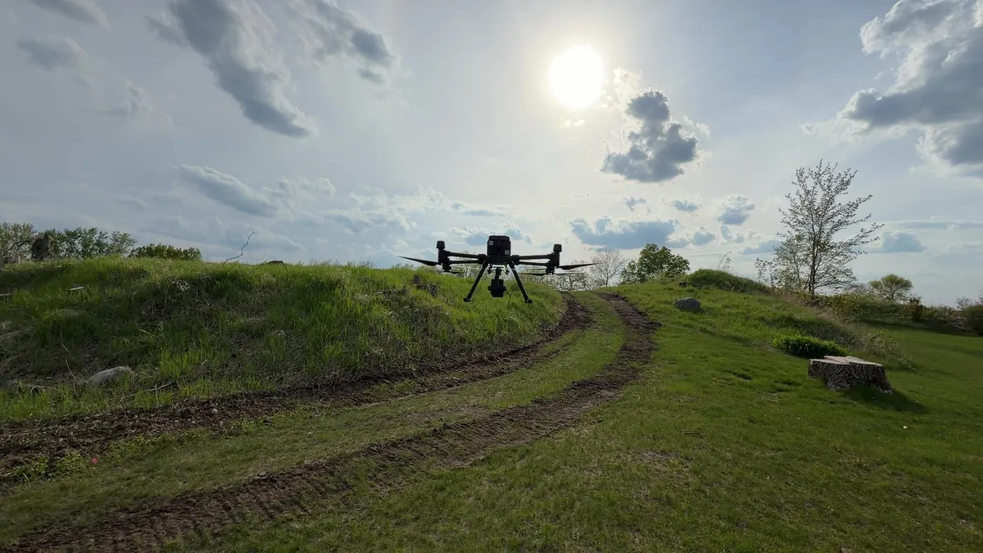 Northern Drone LiDAR drone in flight over a grassy hillside with the sun behind it